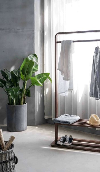 gray dress shirt hang on brown wooden rack in front of window with white curtain